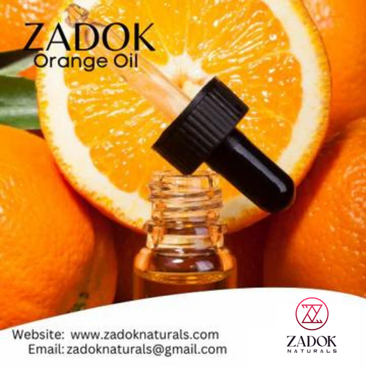 A small bottle of Zadok Naturals Orange Oil with a black cap, positioned in front of a slice of orange and a whole orange behind it, against a white background.